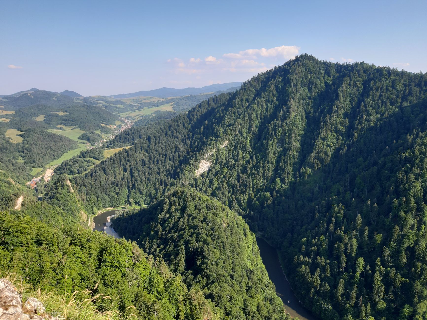 Hiker walking along a narrow trail at the base of a dramatic limestone gorge with a clear river below