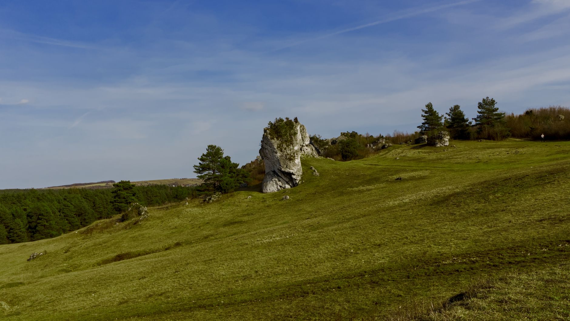 Hiker approaching a historic castle on a steep rocky path with mountain views below