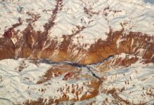 Narrow mountain valley in the Hindu Kush range with terraced hillsides and traditional wooden structures