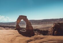 Massive sandstone arch rising above a desert canyon floor in warm afternoon light