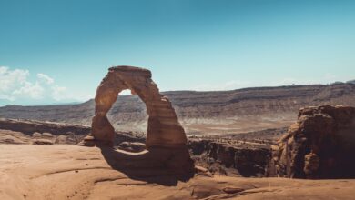 Massive sandstone arch rising above a desert canyon floor in warm afternoon light