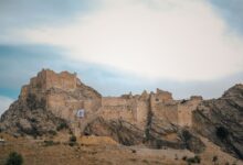 Ancient stone fortress ruins on a rocky mountain ridge against a clear sky