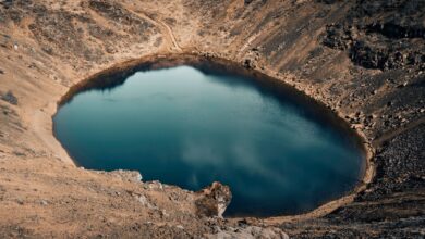Aerial view of Quilotoa volcanic crater lake with turquoise water surrounded by Andean highlands