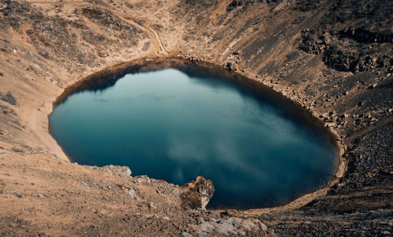 Aerial view of Quilotoa volcanic crater lake with turquoise water surrounded by Andean highlands