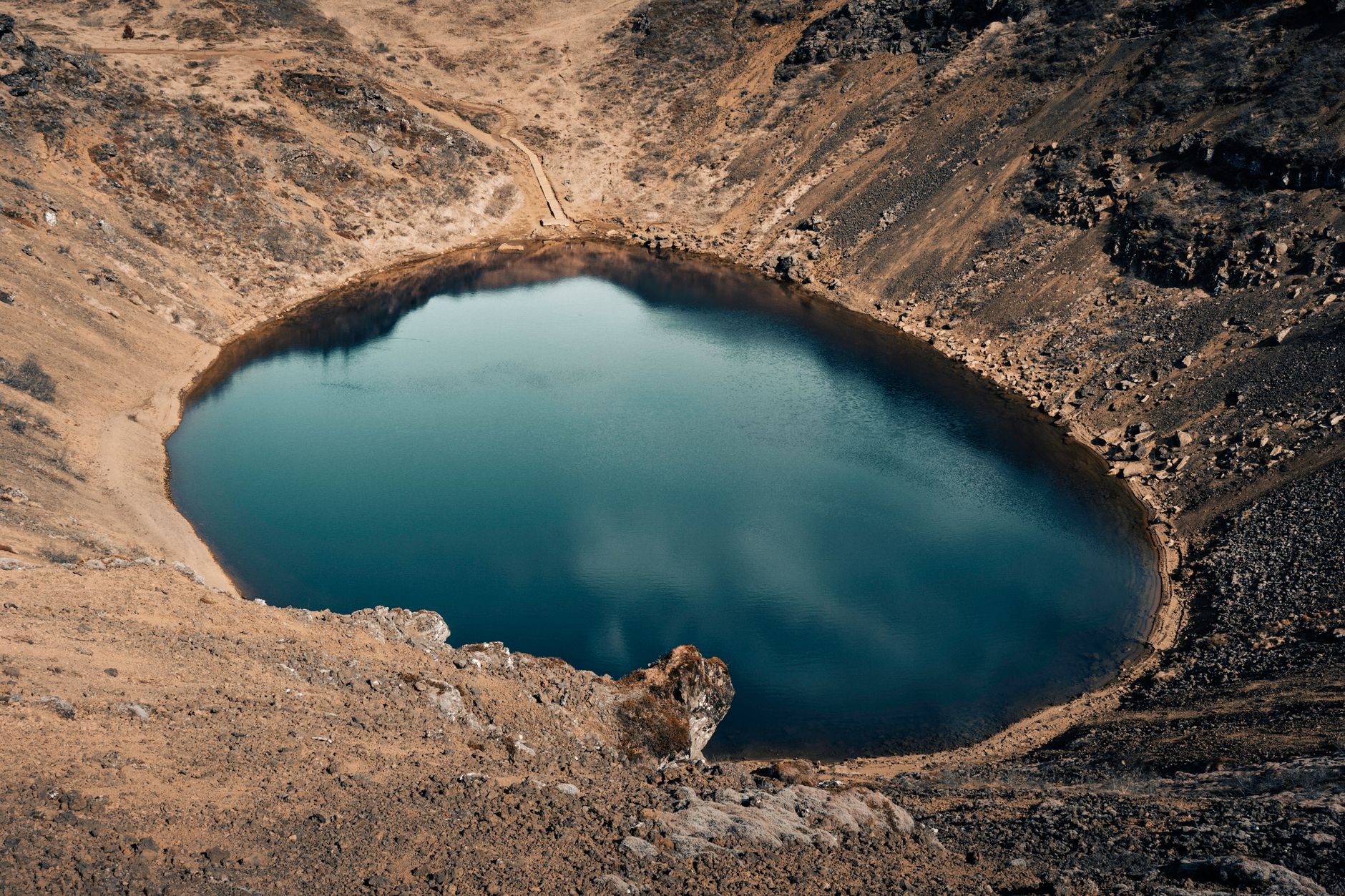 Aerial view of Quilotoa volcanic crater lake with turquoise water surrounded by Andean highlands
