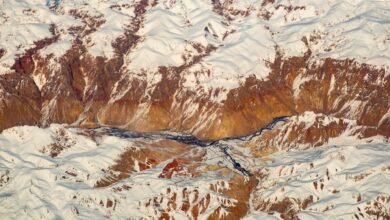 Narrow mountain valley in the Hindu Kush range with terraced hillsides and traditional wooden structures
