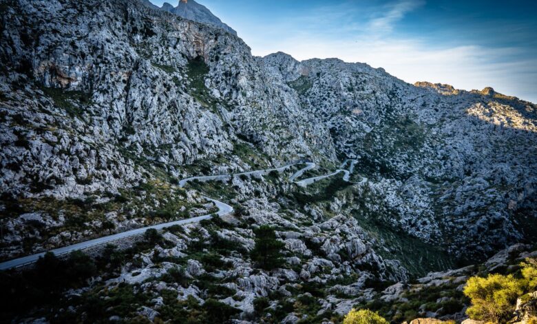 A winding gravel mountain road climbing steep switchbacks through highland terrain