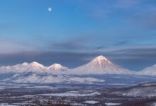 Snow-capped stratovolcano rising above an altiplano landscape at dawn