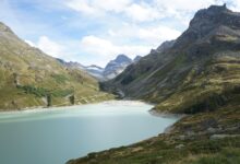 A turquoise alpine lake surrounded by forested mountain ridges in Central Asia