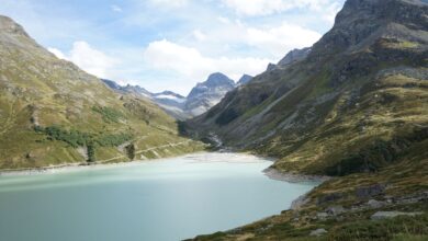 A turquoise alpine lake surrounded by forested mountain ridges in Central Asia