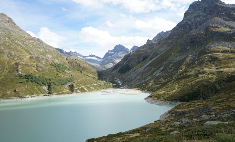 A turquoise alpine lake surrounded by forested mountain ridges in Central Asia