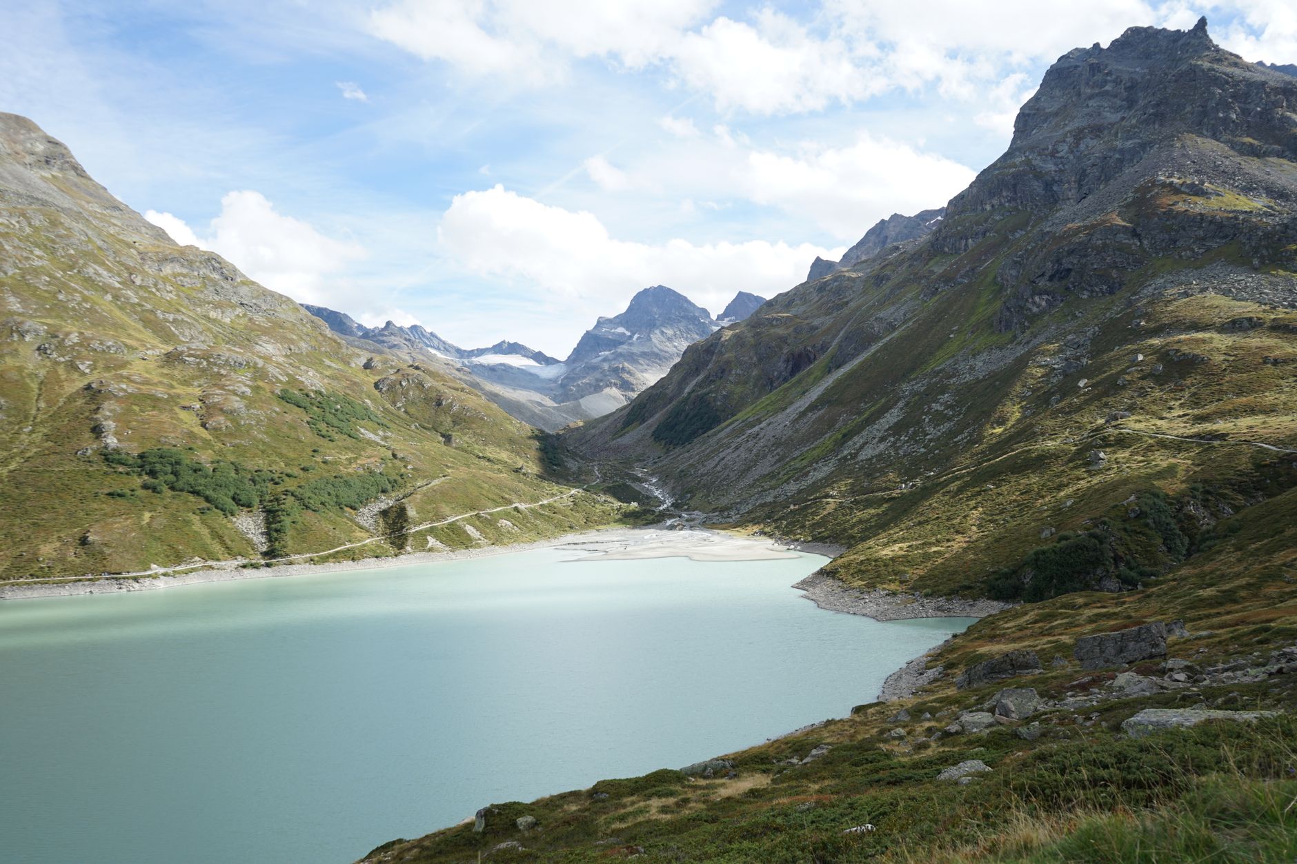 A turquoise alpine lake surrounded by forested mountain ridges in Central Asia