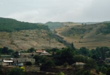 A remote village nestled in a narrow mountain canyon with red and orange rock walls