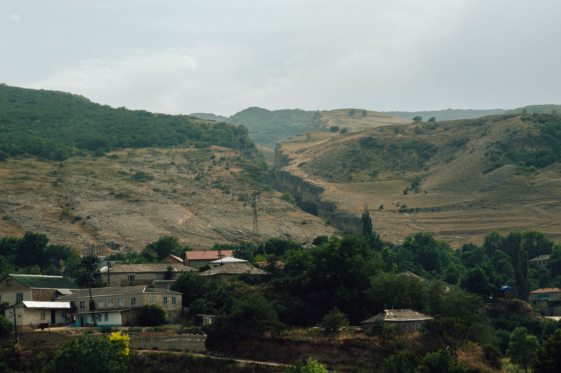 A remote village nestled in a narrow mountain canyon with red and orange rock walls
