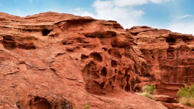 Red sandstone rock formations rising from a green meadow in Central Asia