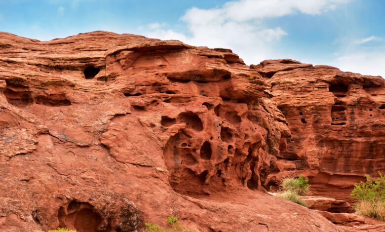 Red sandstone rock formations rising from a green meadow in Central Asia