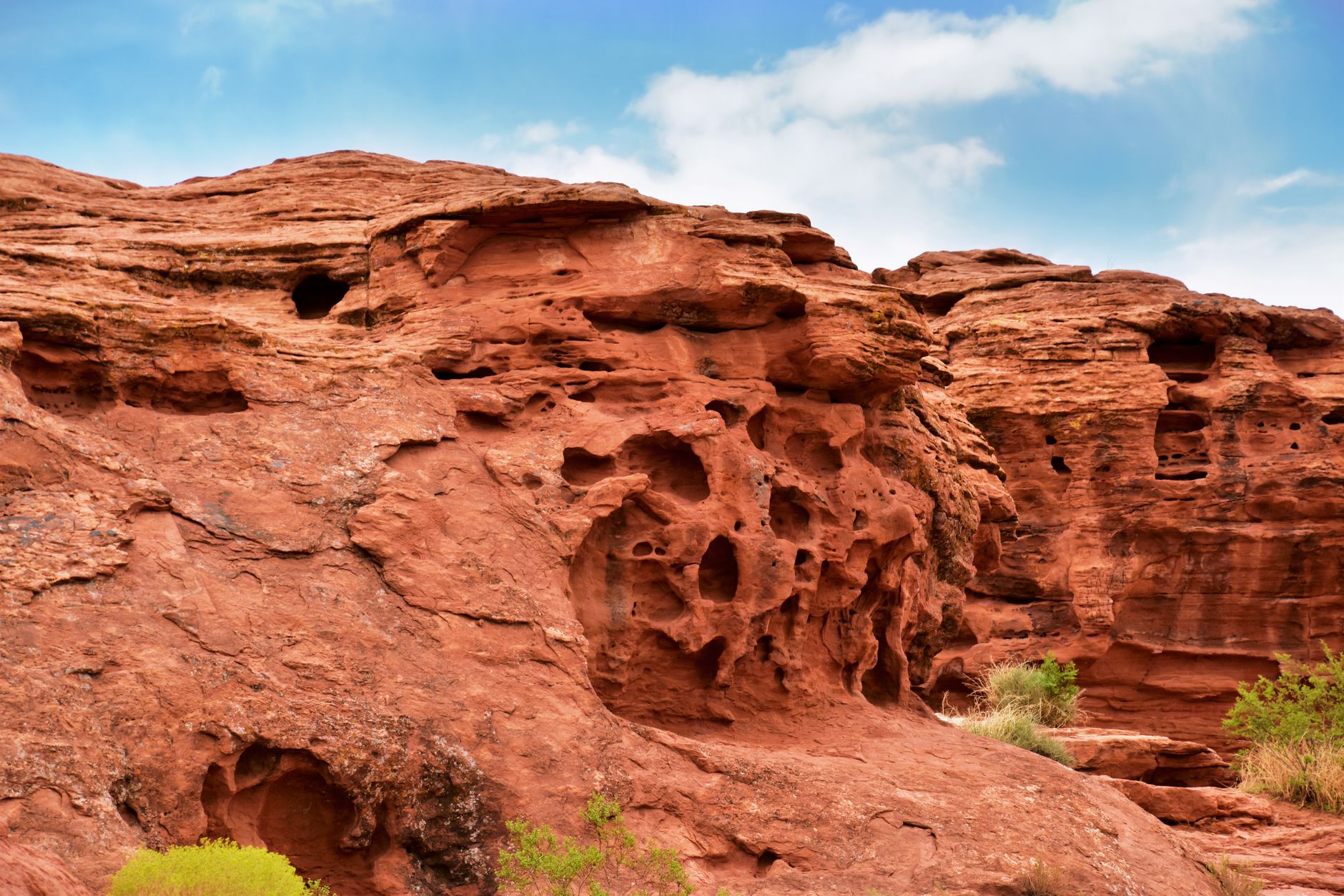 Red sandstone rock formations rising from a green meadow in Central Asia