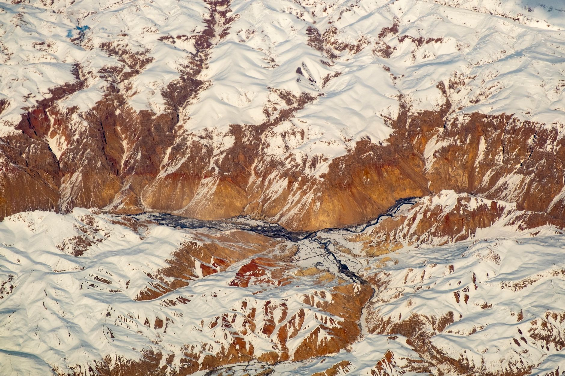 Narrow mountain valley in the Hindu Kush range with terraced hillsides and traditional wooden structures