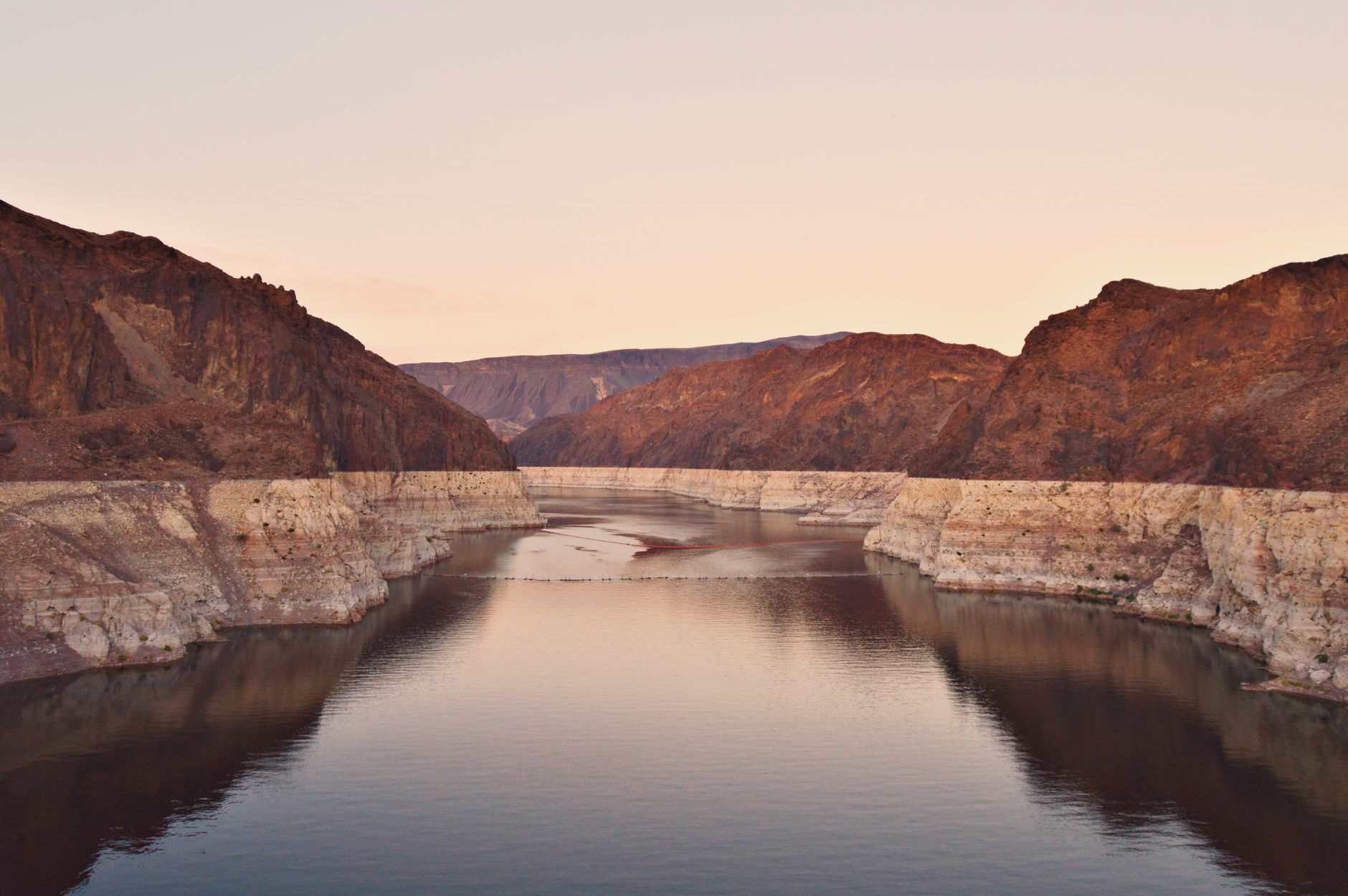 Wide desert lake reflecting orange sunset light with sandy shores in the foreground