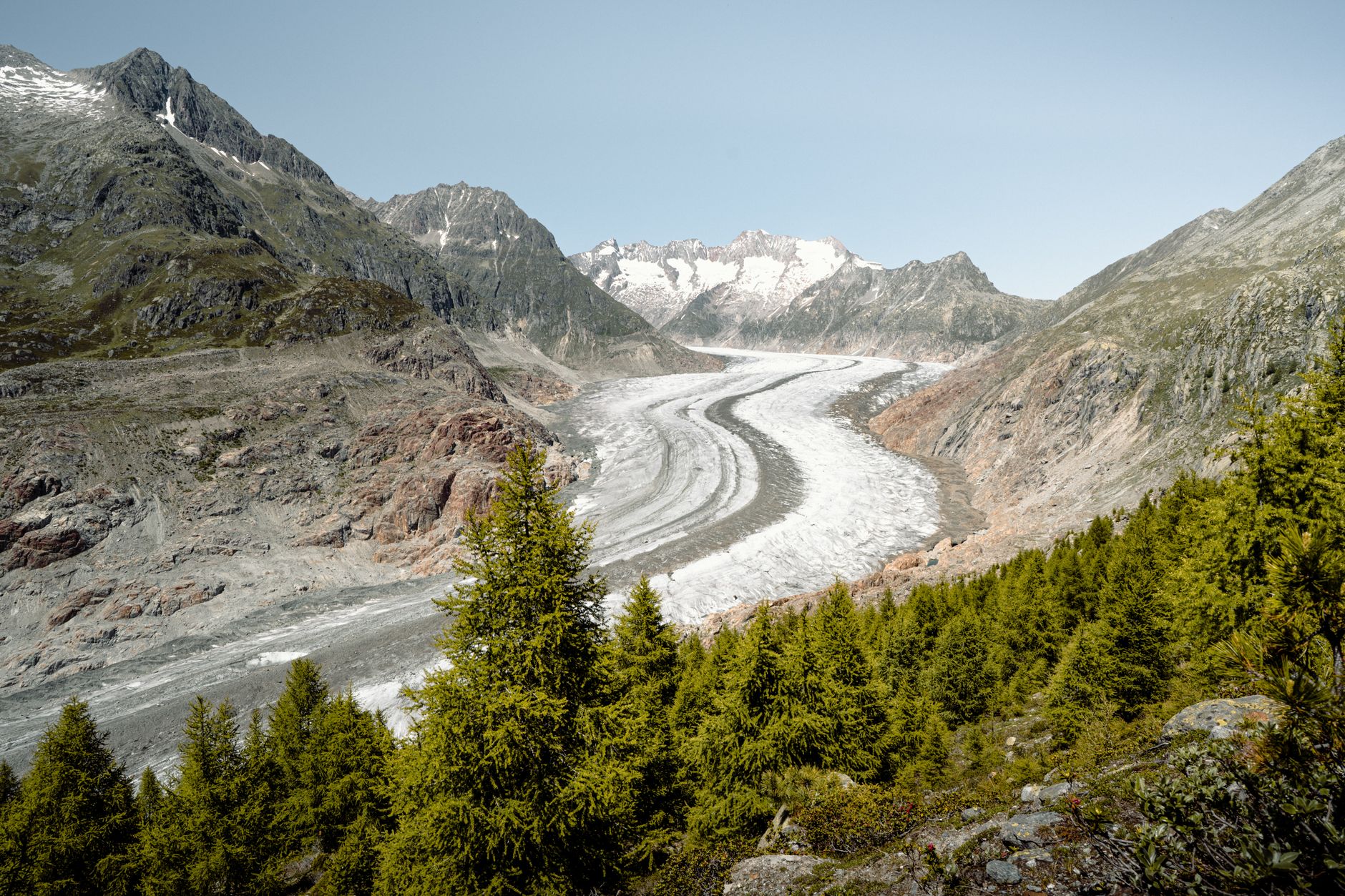 Trekker crossing a high-altitude glaciated mountain pass with expansive Andean terrain visible below