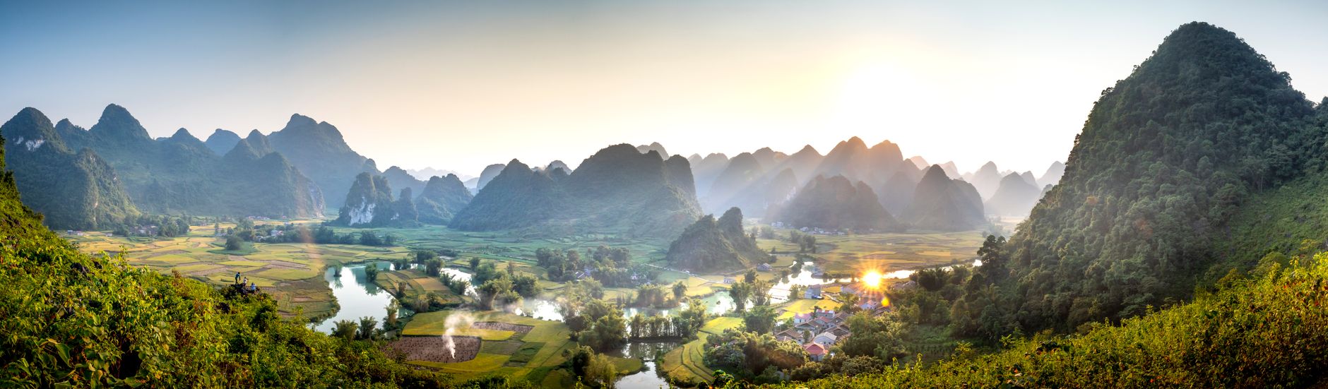 Dramatic limestone karst peaks rising above a green river valley in Ha Giang province