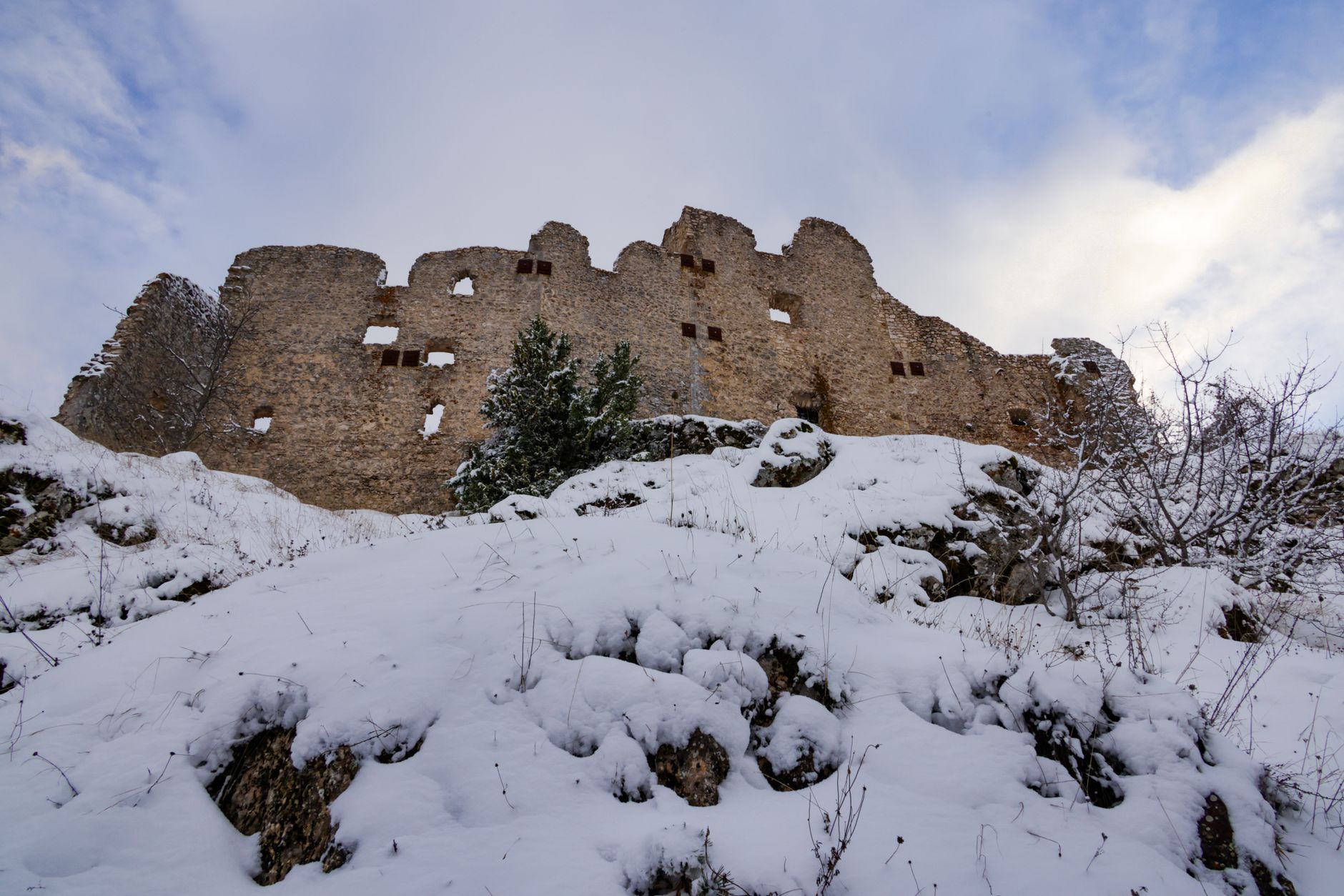Ancient stone fortress walls perched on a rocky ridge above a river valley at high altitude