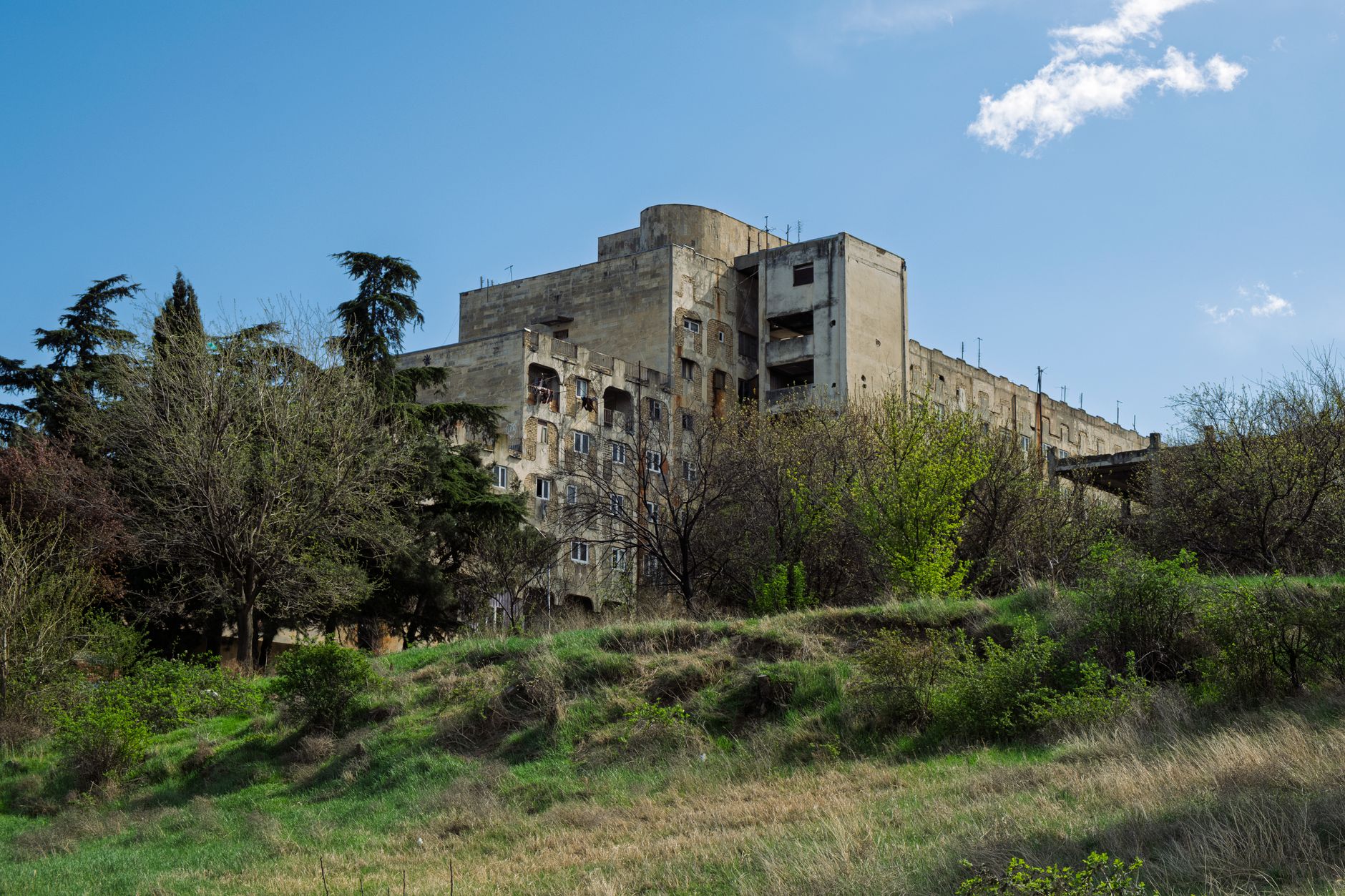 Faded Soviet-era administrative building with painted murals on an exterior plaster wall
