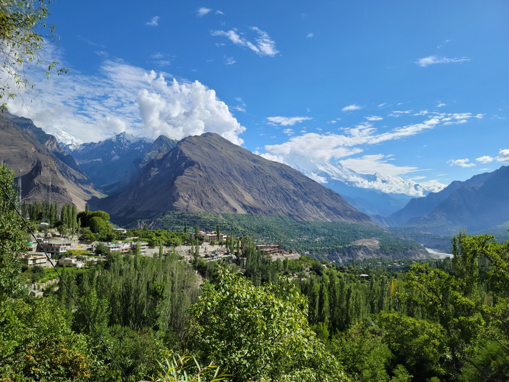 Traditional mountain village with stone and timber houses stacked on a steep hillside in northern Pakistan