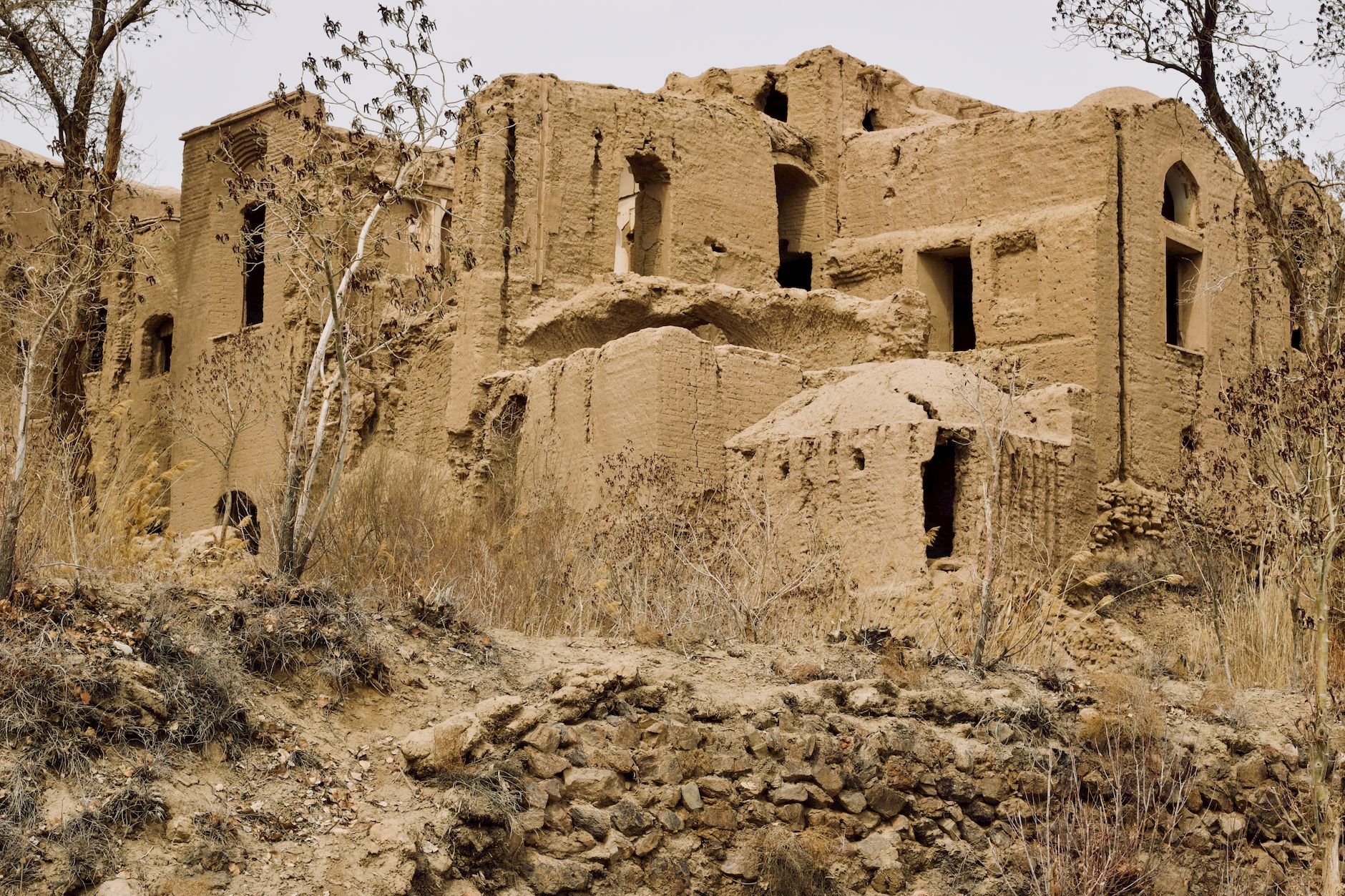 Stepped mud-brick ziggurat ruins rising from flat desert landscape under open sky