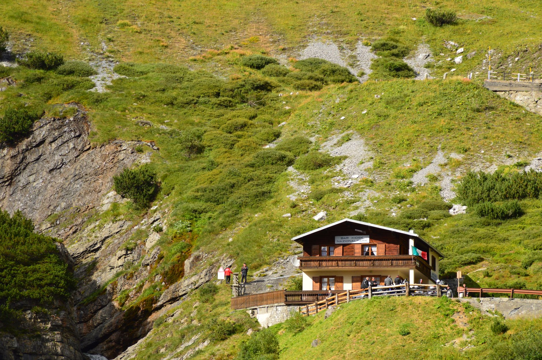 Small traditional guesthouse nestled in a mountain village surrounded by forest and peaks