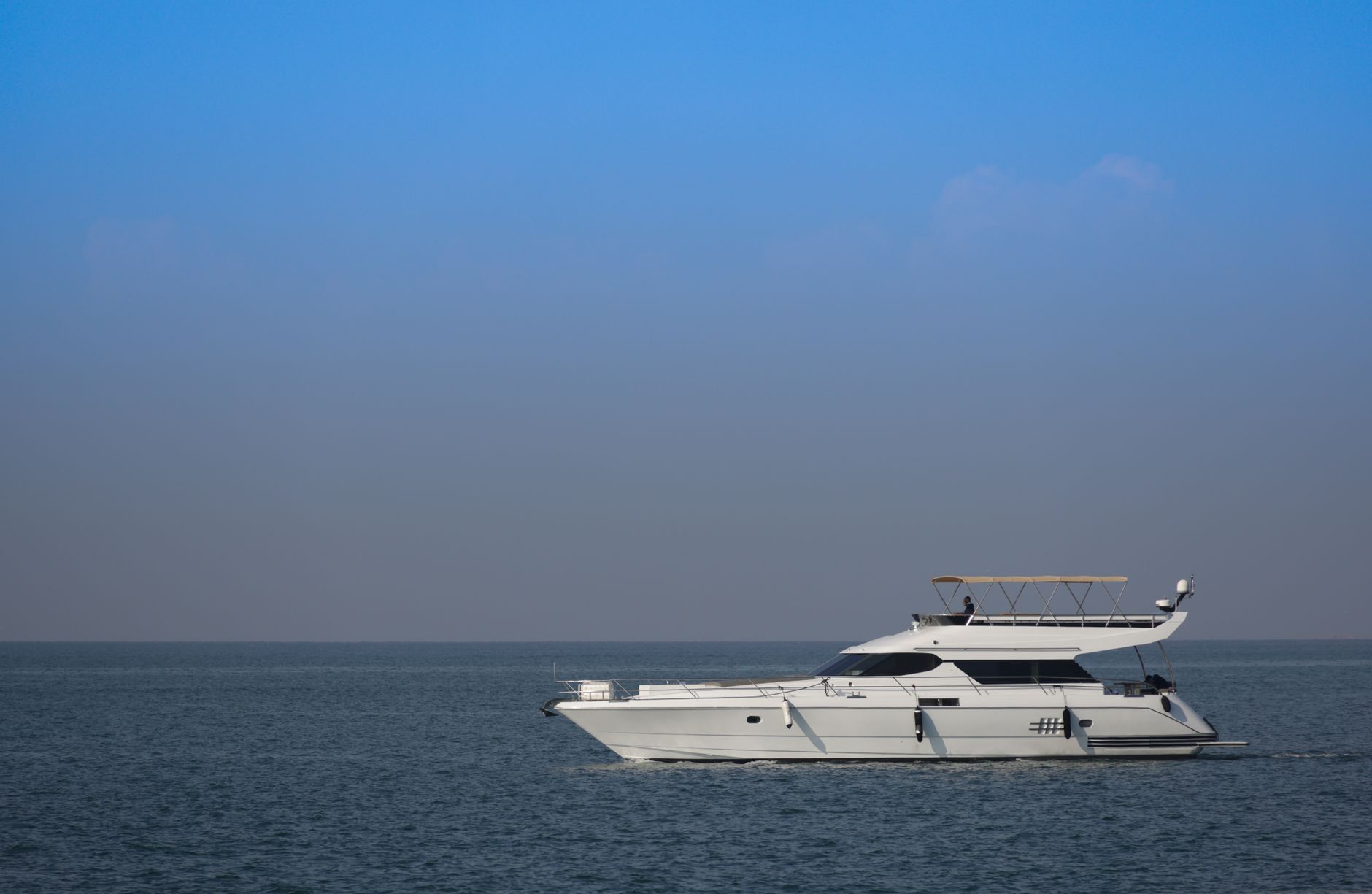 Small expedition liveaboard vessel anchored near a forested tropical island at dusk