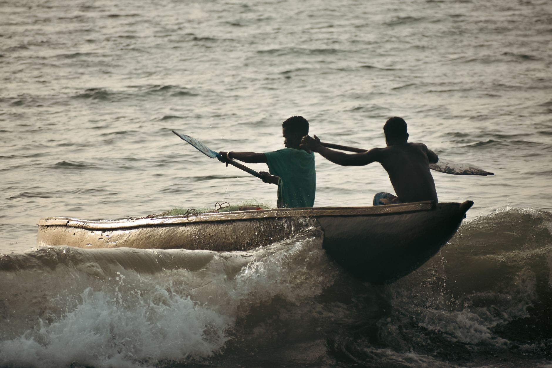 A traditional dugout canoe moving along a remote jungle river at dusk