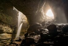 Massive cave chamber with stalactites and dramatic lighting inside a karst cave system