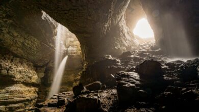 Massive cave chamber with stalactites and dramatic lighting inside a karst cave system
