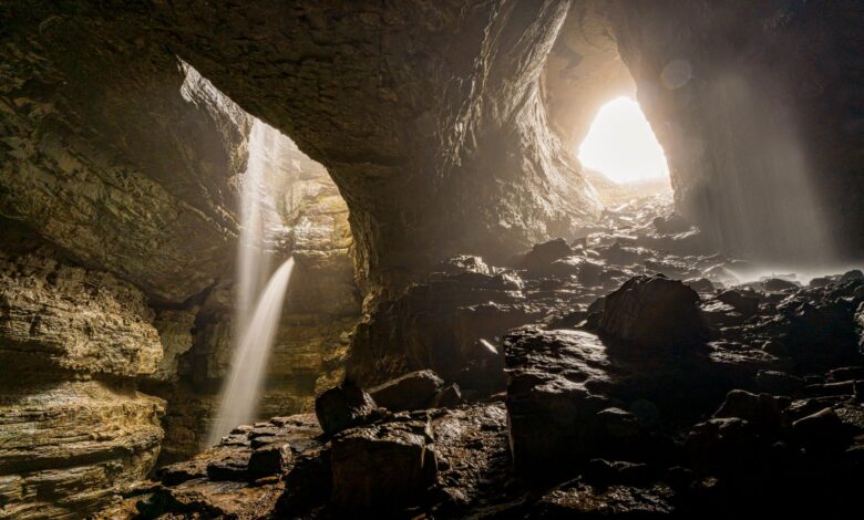 Massive cave chamber with stalactites and dramatic lighting inside a karst cave system