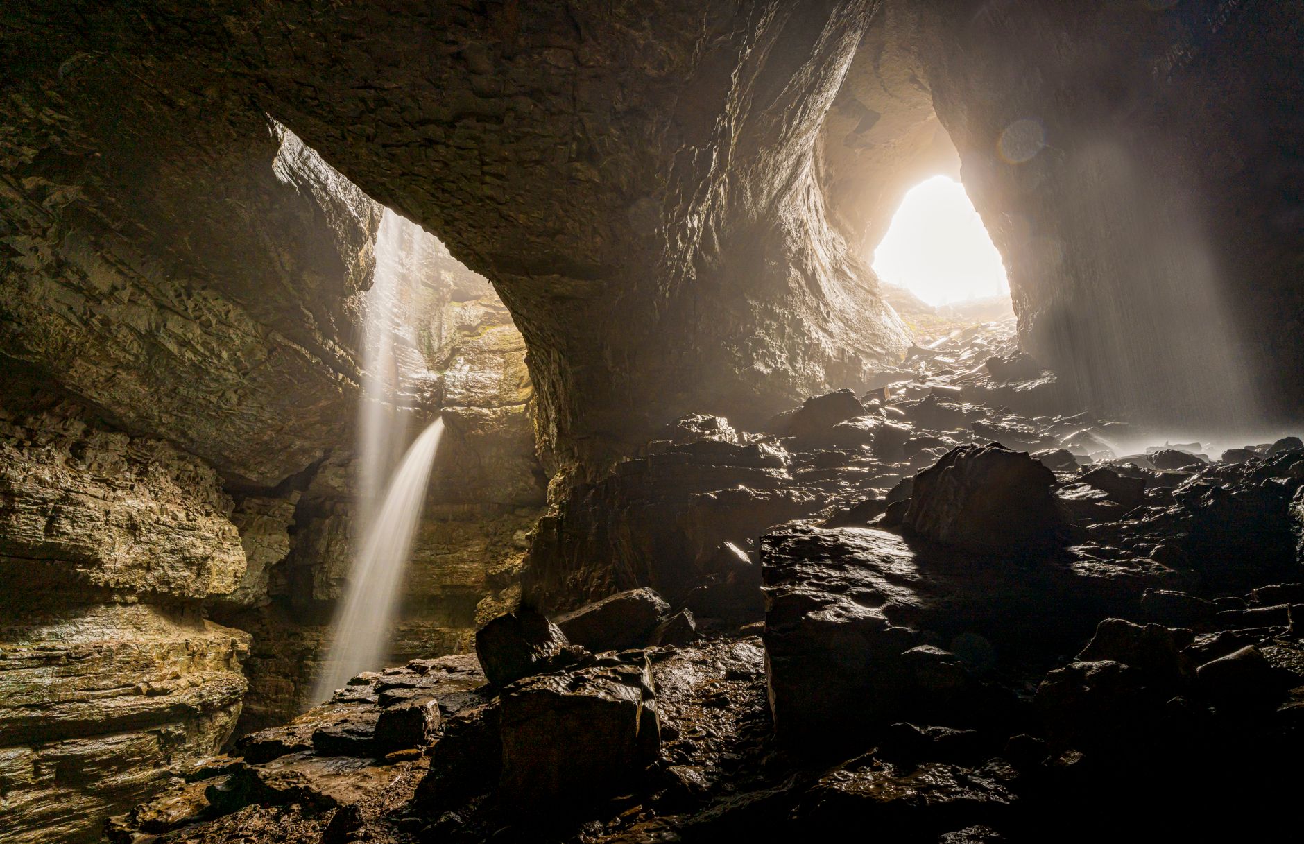 Massive cave chamber with stalactites and dramatic lighting inside a karst cave system