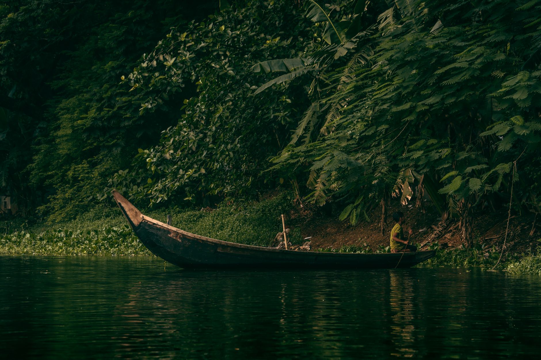 A dugout canoe navigating a narrow jungle river in lowland Papua New Guinea