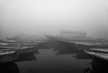 Misty lake at dawn with traditional wooden fishing boats on calm water