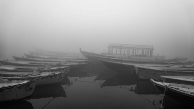 Misty lake at dawn with traditional wooden fishing boats on calm water