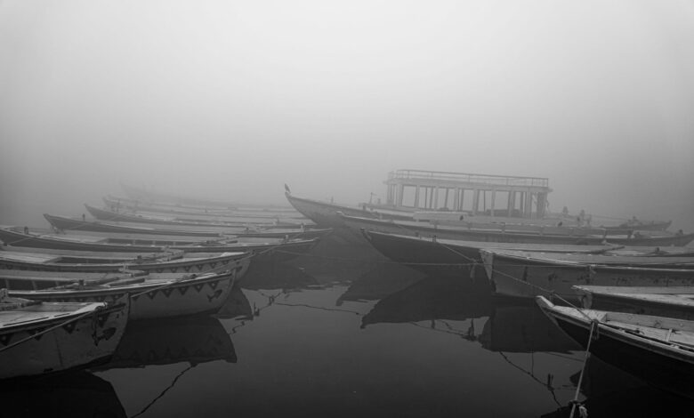 Misty lake at dawn with traditional wooden fishing boats on calm water