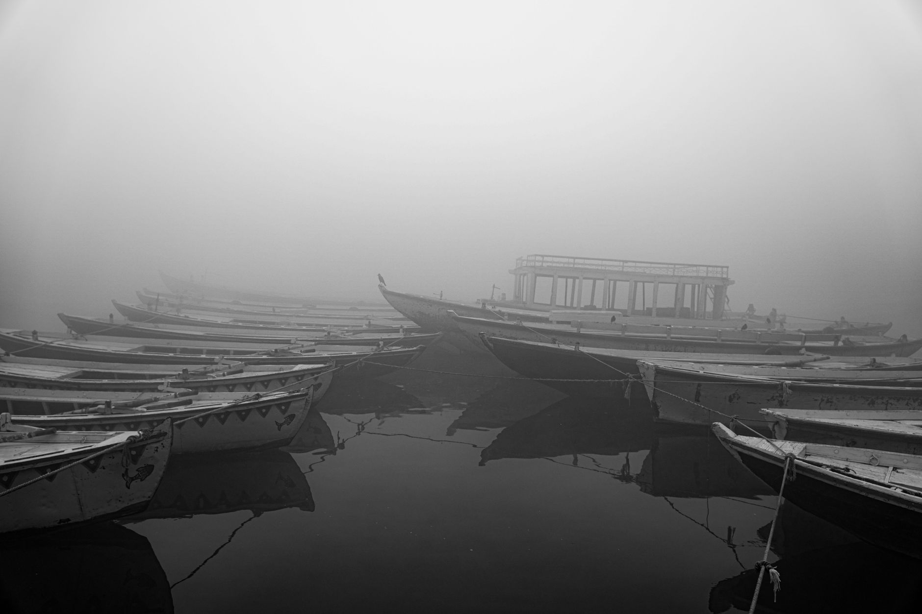 Misty lake at dawn with traditional wooden fishing boats on calm water