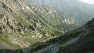 A steep winding gravel mountain road climbing through dramatic highland terrain