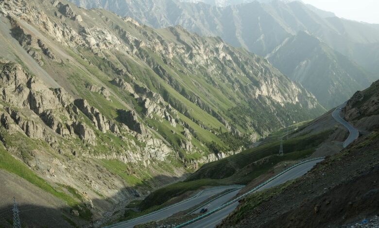 A steep winding gravel mountain road climbing through dramatic highland terrain