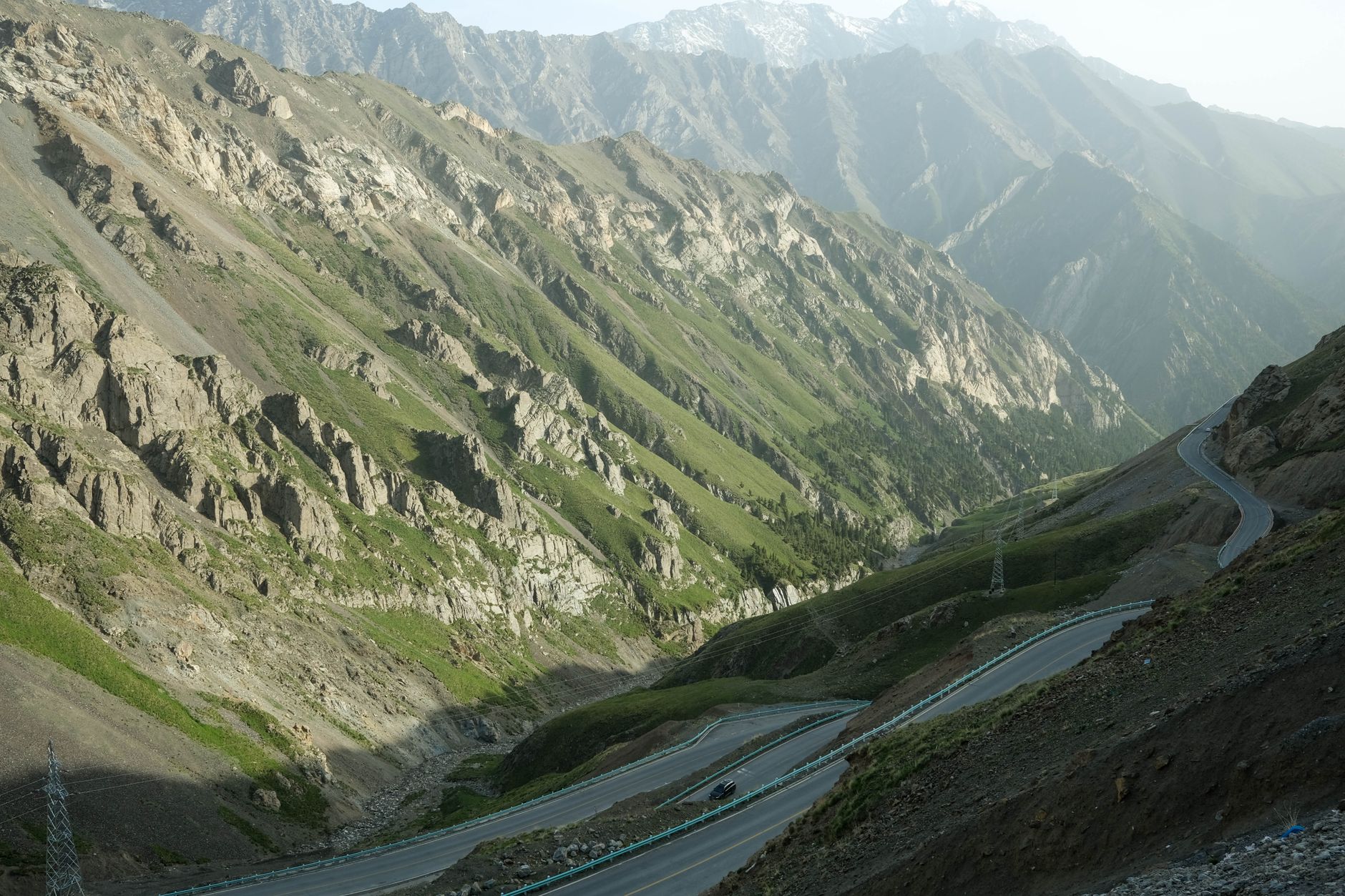 A steep winding gravel mountain road climbing through dramatic highland terrain