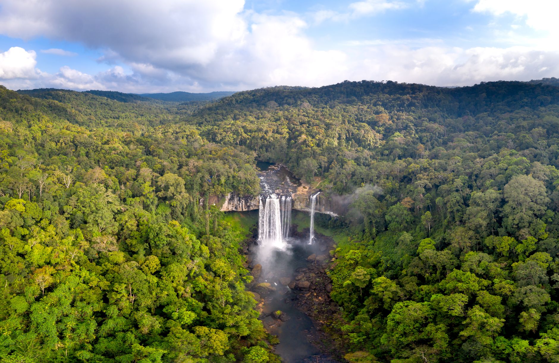 A dramatic waterfall surrounded by dense jungle vegetation on the Bolaven Plateau