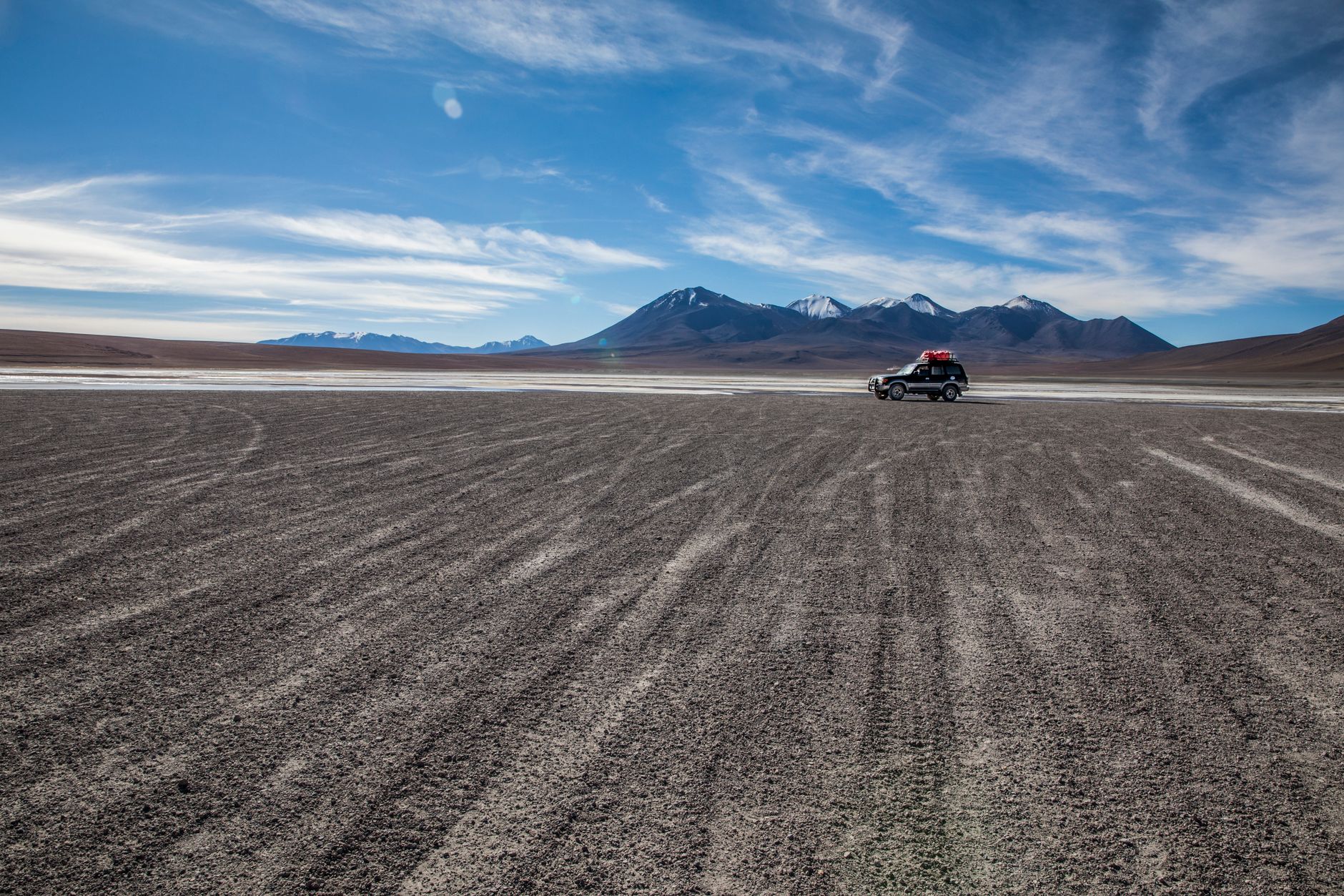 A 4x4 jeep driving across a remote high-altitude landscape in the Bolivian altiplano