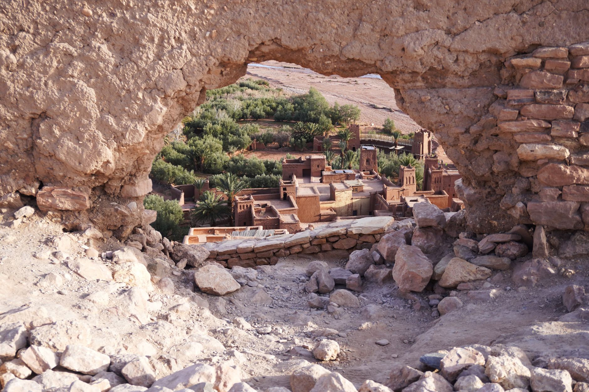 Traditional mud-brick Moroccan kasbah fortress walls glowing ochre in afternoon sunlight against a clear blue sky