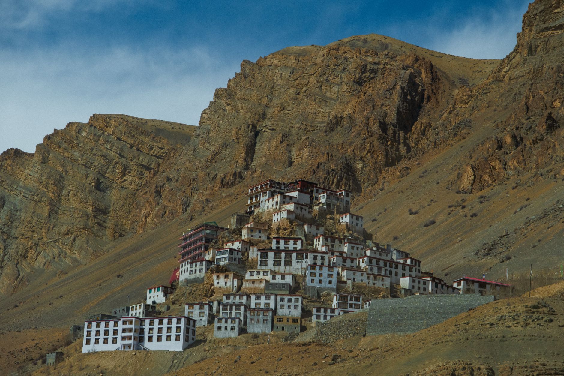 Ancient stone monastery set against forested Himalayan ridgeline under clear sky