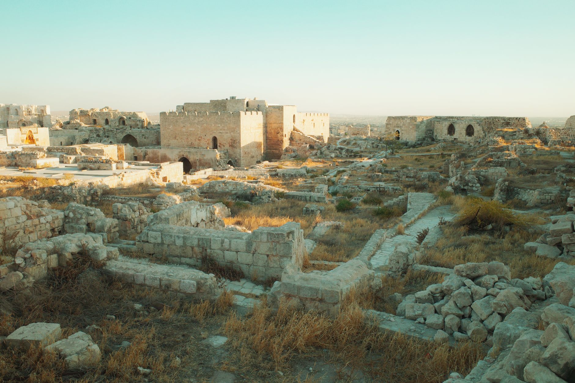 Weathered stone ruins of a historic fortress perched on a hillside above a river valley