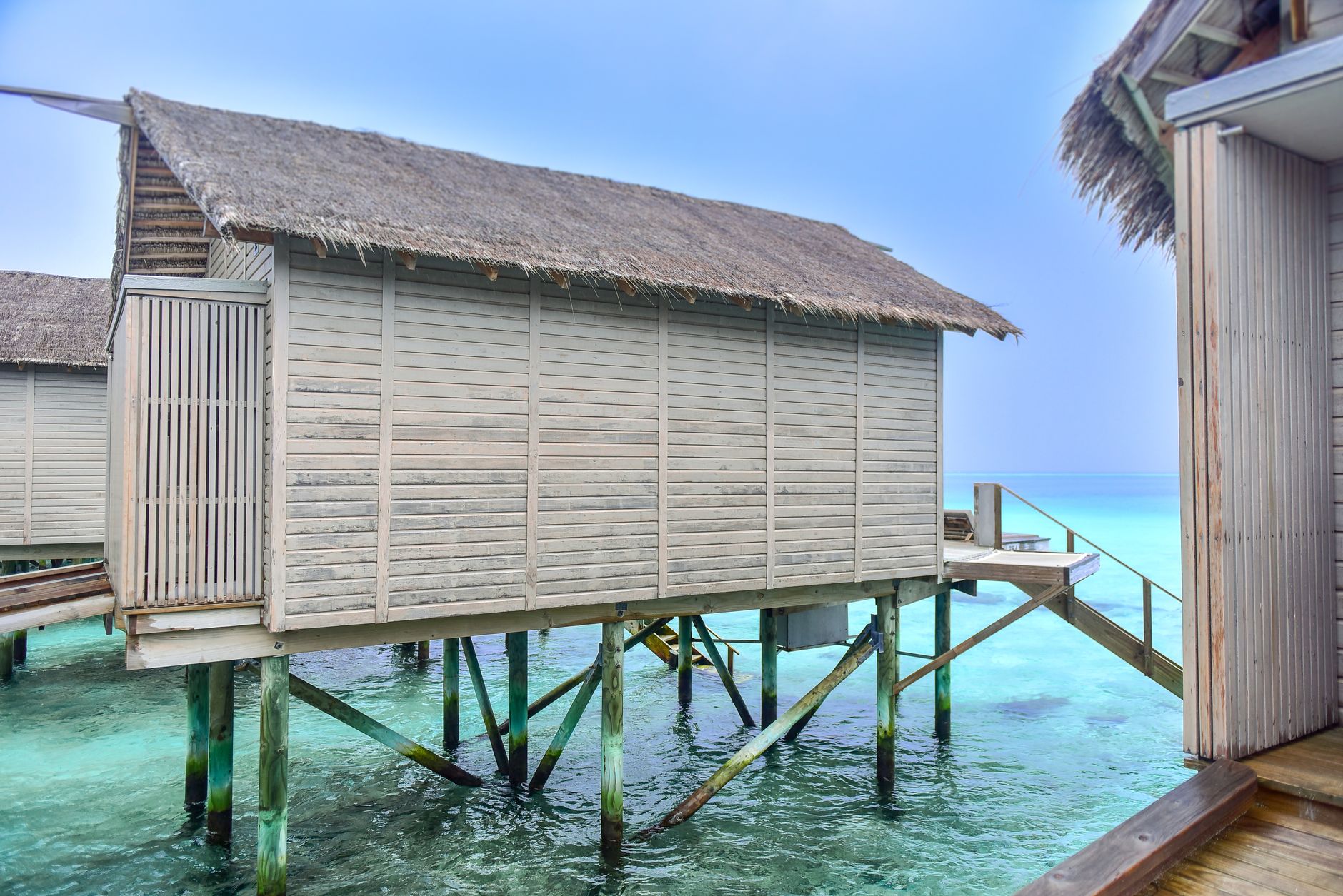 Wooden overwater bungalows on stilts above turquoise tropical water